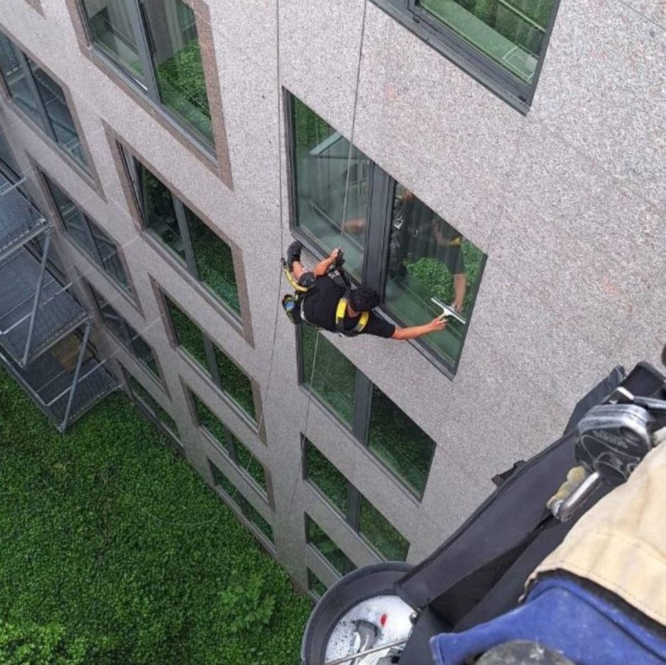 Ruitenwasser hangt aan een touw en wast een raam op grote hoogte